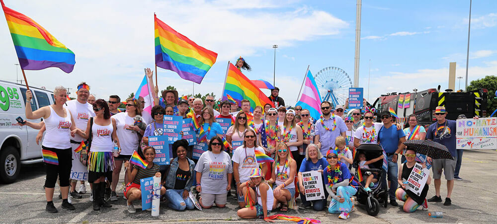 Group of people in rainbow colors and a rainbow flag